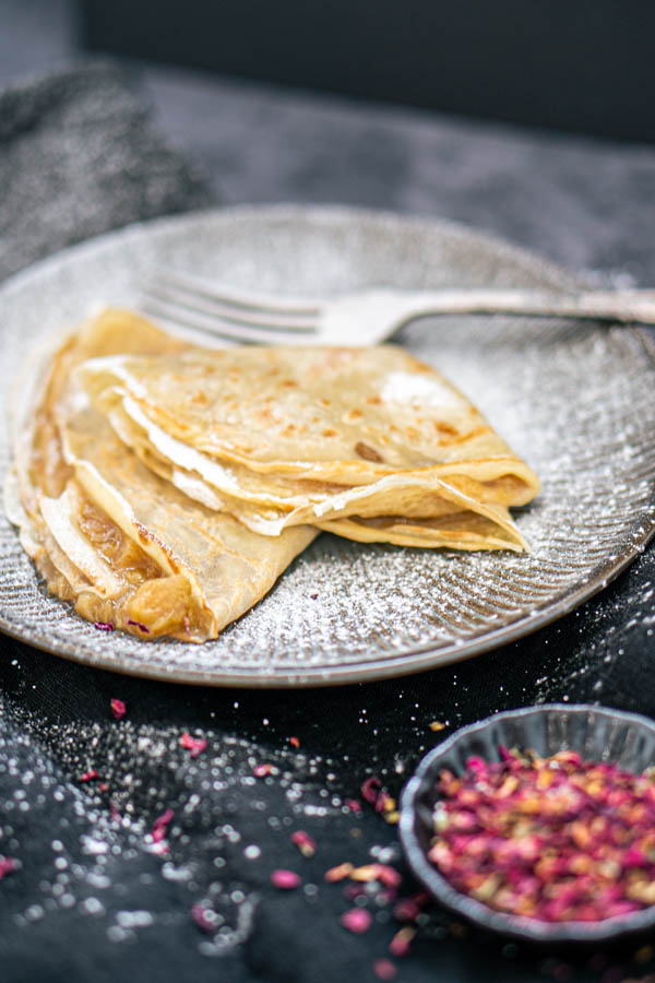 A plate with rhubarb crêpes and a side dish with rose petals